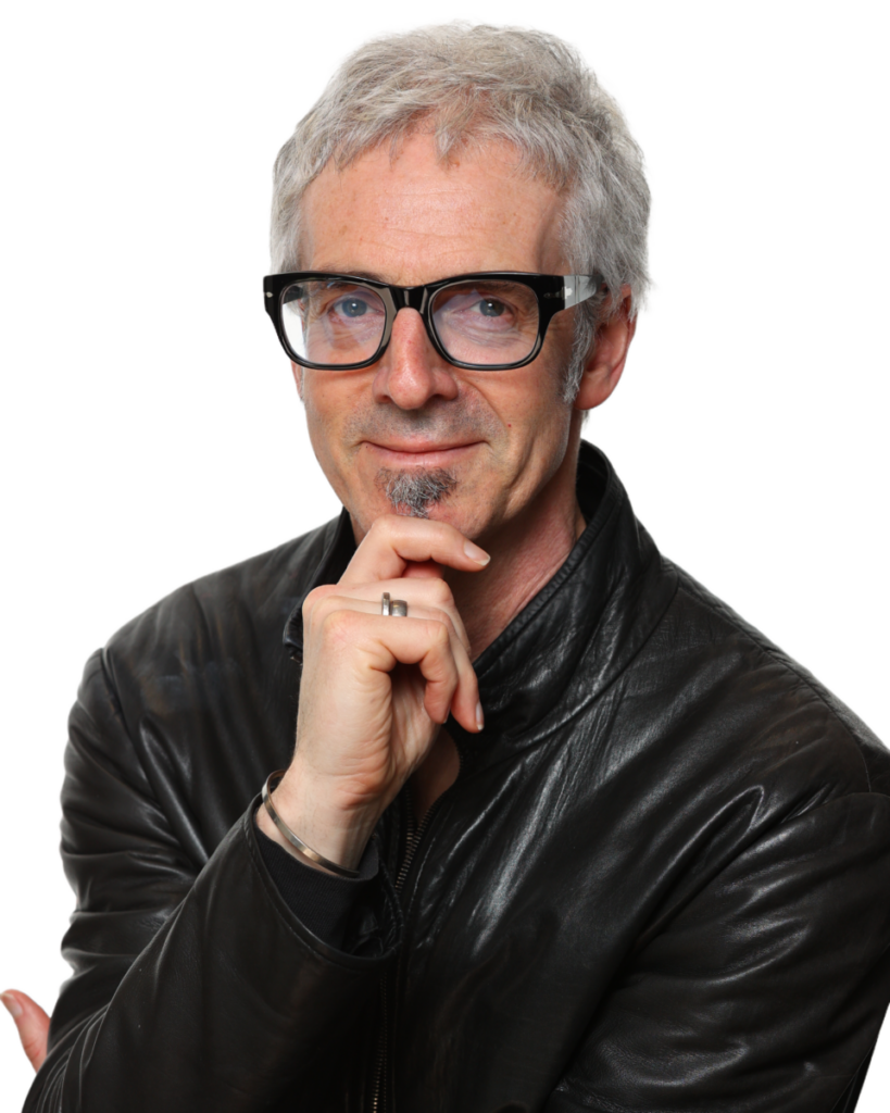 Man with glasses and gray hair in a black leather jacket, thoughtfully resting his chin on his hand.